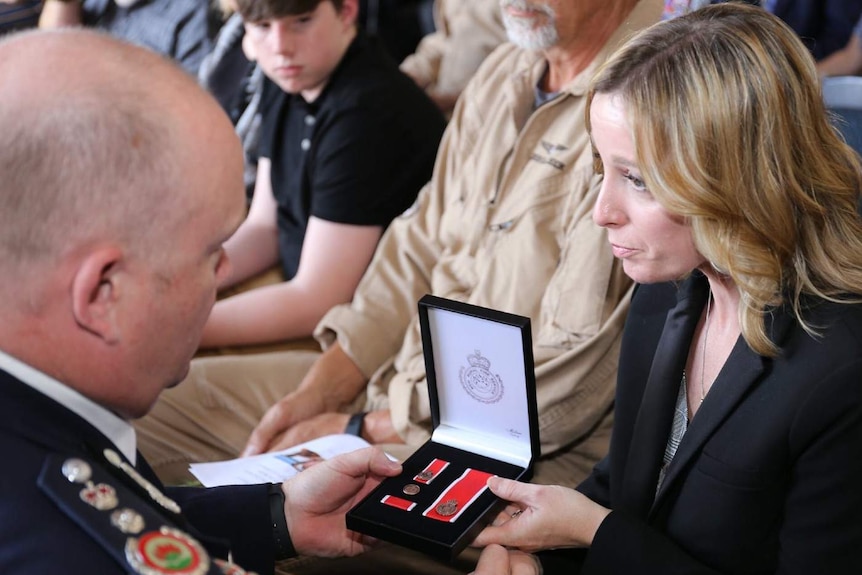 A man gives a medal a woman