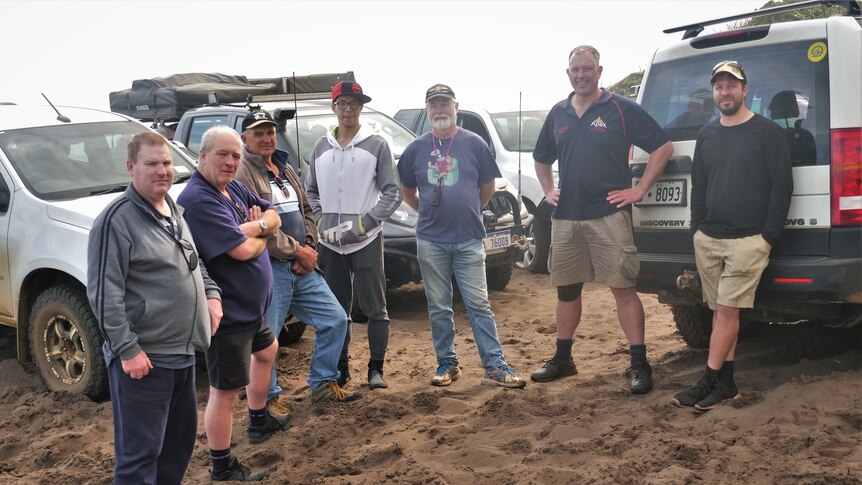 Seven members of the Albany Four-Wheel Drive Club standing in front of their vehicles.