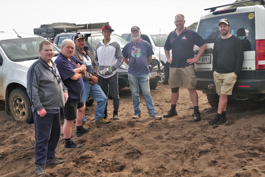 Seven members of the Albany Four-Wheel Drive Club standing in front of their vehicles.