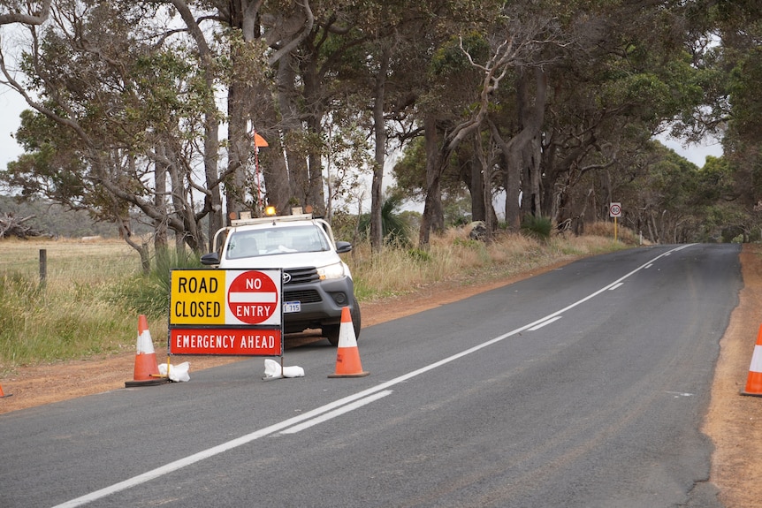 A car and a road closed sign