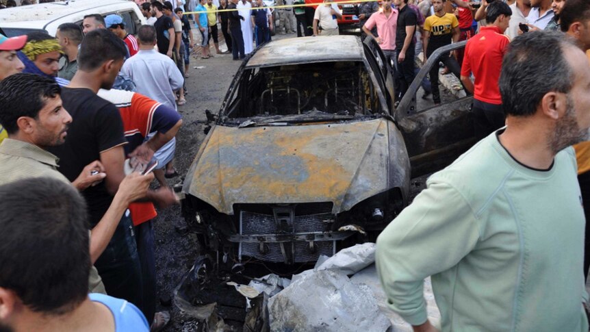 People gather at the site of a deadly car bomb attack in Kut city.