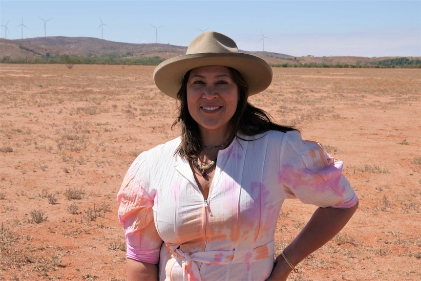 La chanteuse australienne Kate Ceberano debout dans un paysage désertique avec des éoliennes en arrière-plan
