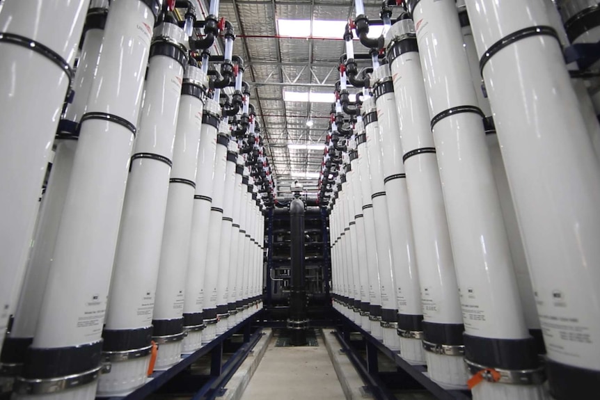 Tall white water filtration tanks inside a groundwater treatment plant.