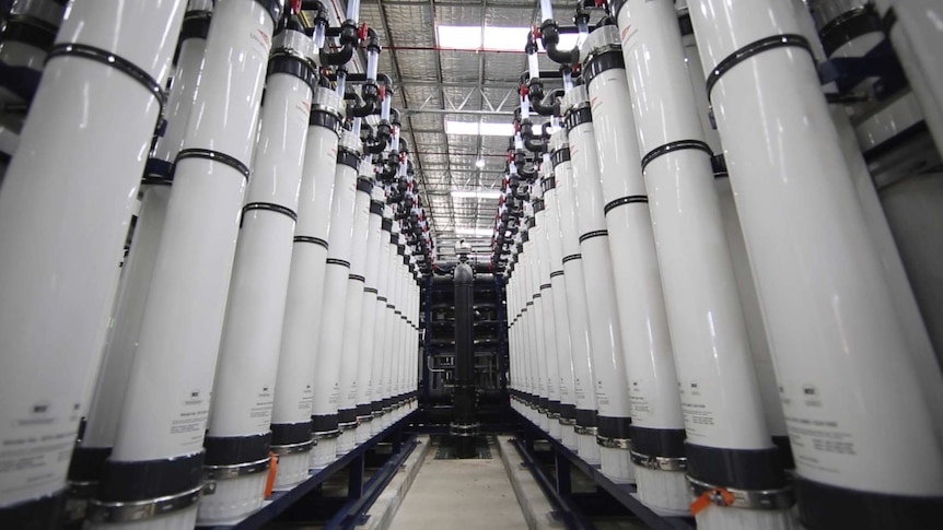 Tall white water filtration tanks inside a groundwater treatment plant.