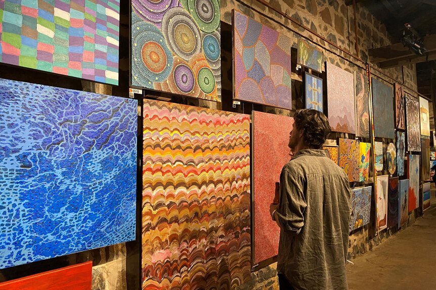 A person looking at artwork hanging on a wall.