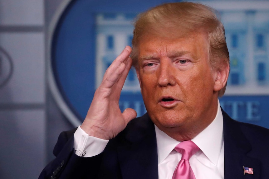 Donald Trump in the White House press briefing room with his hand by his face