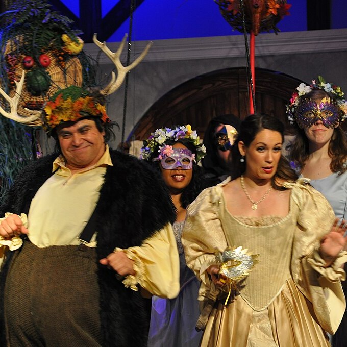 A joyous scene from Falstaff in which the smiling hero wears a hat adorned with moose horns.