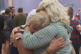 A distraught woman is consoled by another woman after the Apollo Bay community meeting.