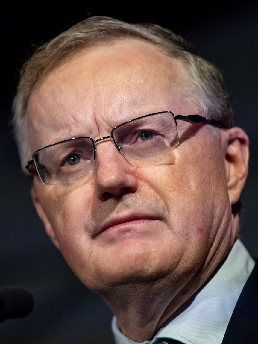 A close shot man wearing a suit against a dark background.