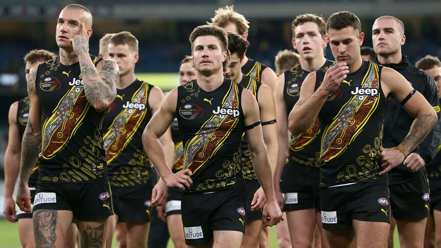 A group of Richmond AFL players walk off the MCG playing area.
