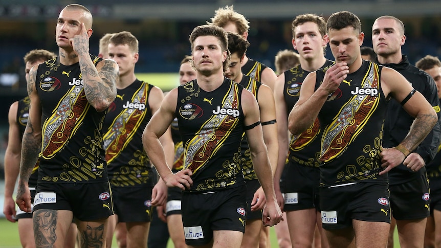 A group of Richmond AFL players walk off the MCG playing area.