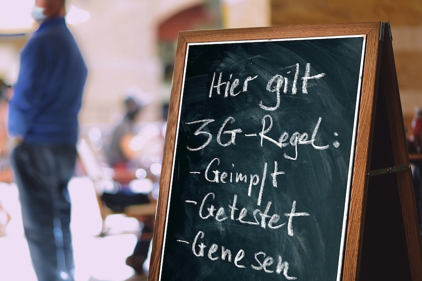 A chalkboard sign 'geimpft, genesen, getestet'.