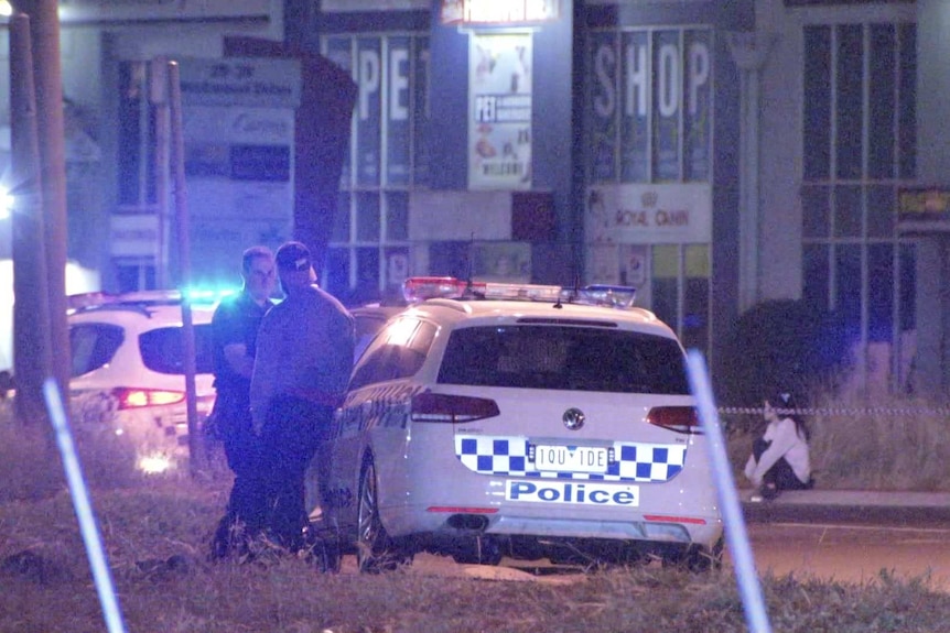 Police at a crime scene in an industrial estate at night.