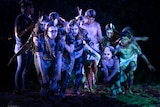 Young indigenous dancers painted in ochre dancing in a tight huddle with stage lights
