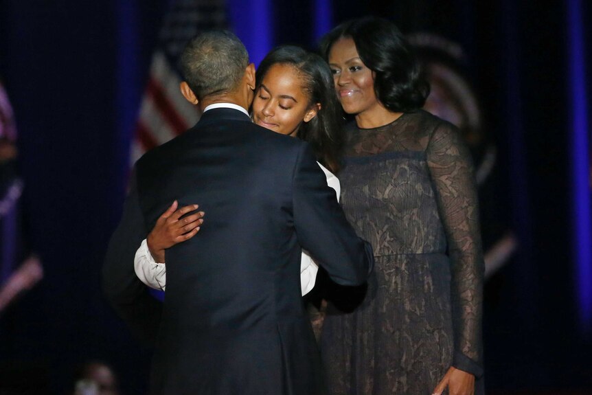 Barack Obama hugs his daughter Malia as First Lady Michelle Obama watches on.