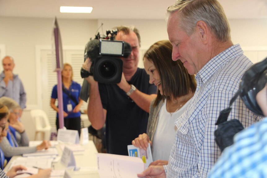 A side shot of Colin Barnett at a ballot box with a cameraman in the background.