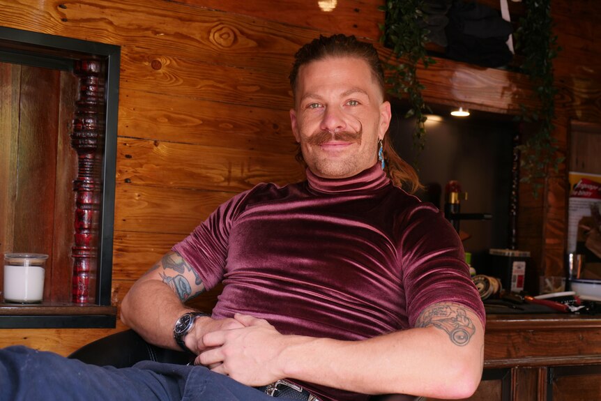 A person with a prominent moustache inside a barber shop.