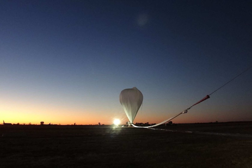 A helium balloon prepares to launch at sunrise in Alice Springs.