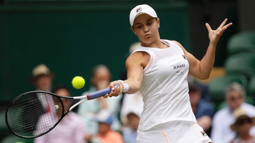 A female tennis player plays a forehand stroke with her racquet to the right of her body as she watches the ball.