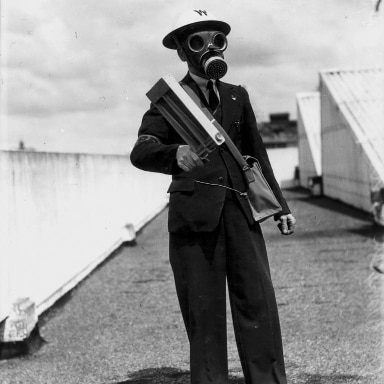 Man in gas mask and helmet holding equipment