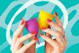 A woman's hands holding a yellow menstrual cup and a pink menstrual cup for a guide on how to use menstrual cups.