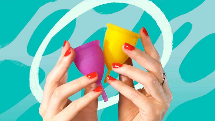 A woman's hands holding a yellow menstrual cup and a pink menstrual cup