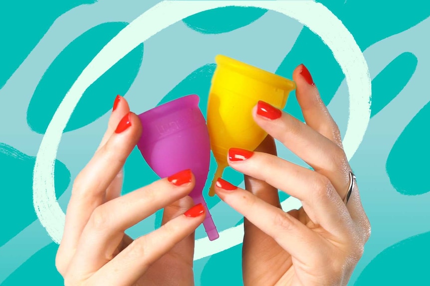 A woman's hands holding a yellow menstrual cup and a pink menstrual cup
