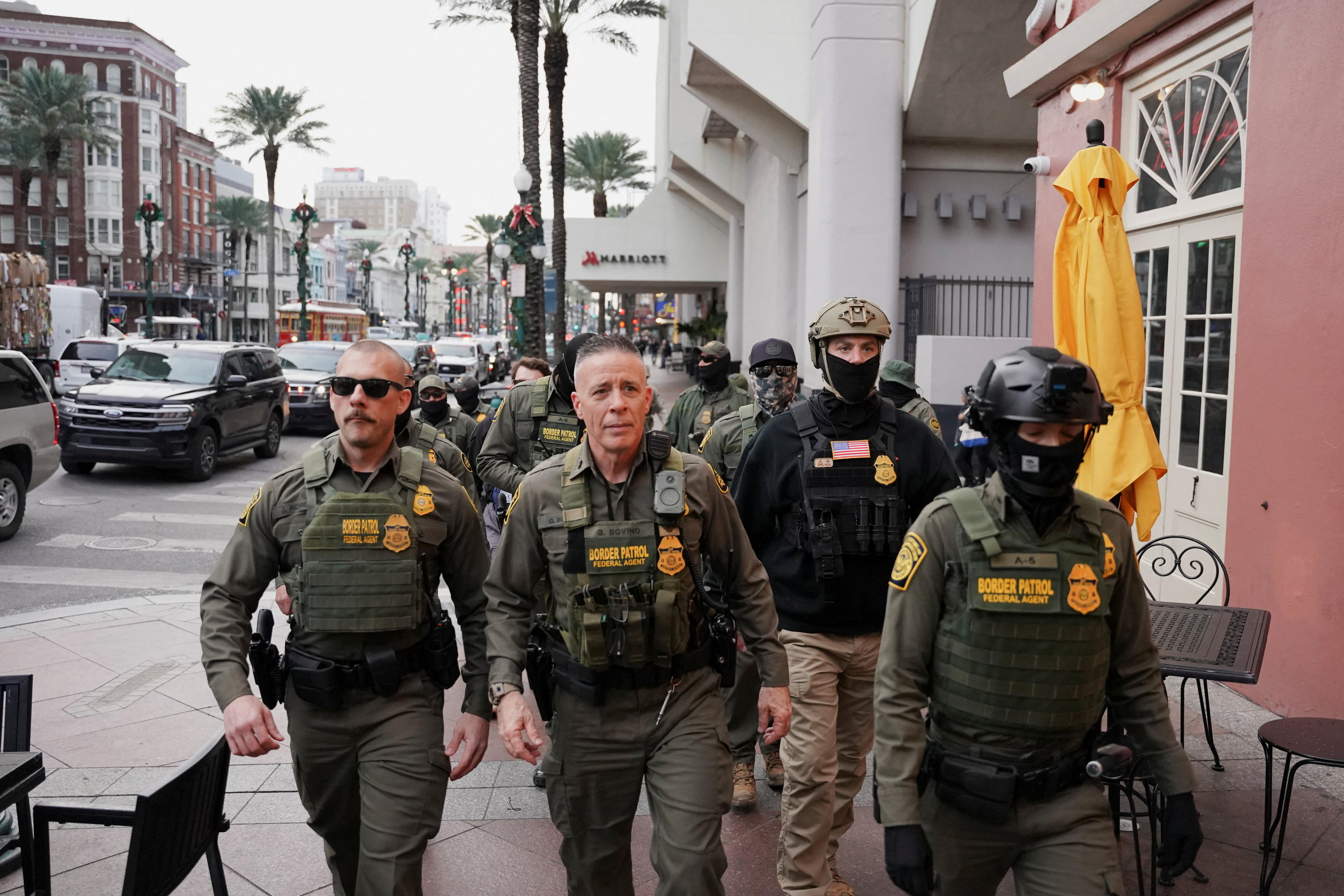 A group of men in heavy military uniforms walk along a busy street.