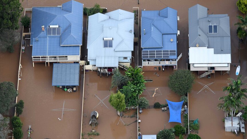 An aerial photograph of floodwaters engulfing four homes in central Lismore.