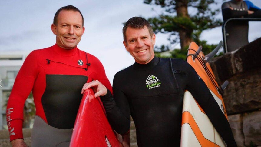 Facebook image of Tony Abbott and Mike Baird in wetsuits, carrying surfboards.