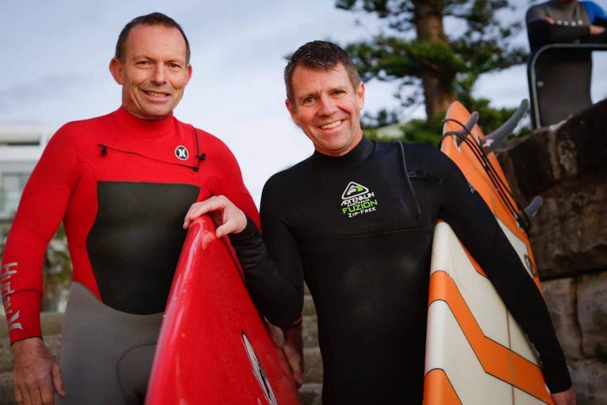 Facebook image of Tony Abbott and Mike Baird in wetsuits, carrying surfboards.