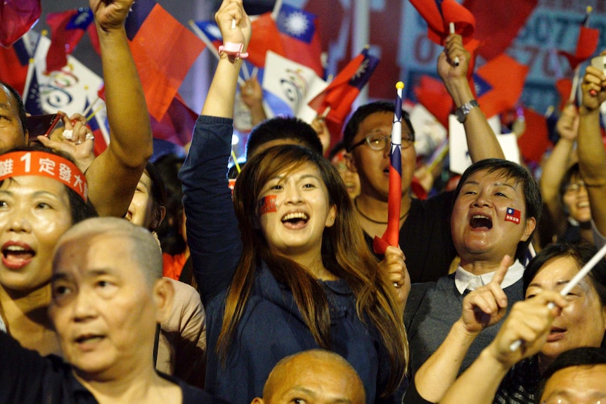 Crowd of Kuomintang supporters wave Taiwanese flags with miniature flags stuck onto supporters' cheeks.