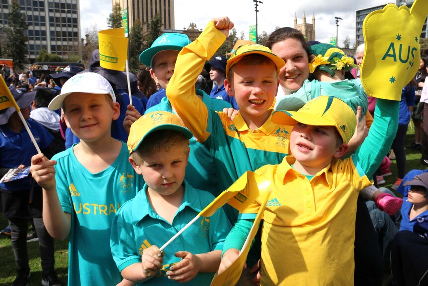 Children dressed in green and gold wave flags