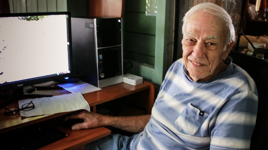 An elderly man sitting at a computer .
