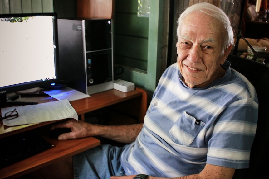 An elderly man sitting at a computer .