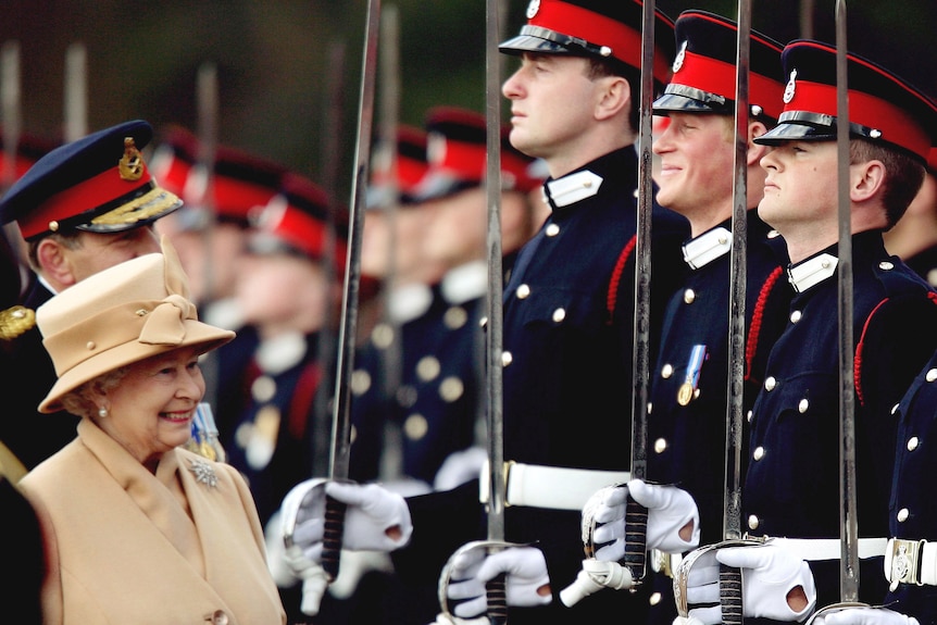 Queen Elisabeth III smiles as Prince Harry stands as part of the Sovereign's Parade at the Royal Military Academy. 