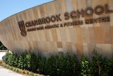 A curved sandstone wall with the words 'Cranbrook School  Murray Rose Aquatic & Fitness Centre'.