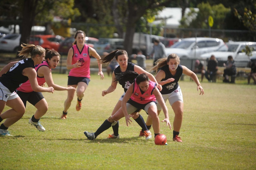 A group of female AFL players compete for the ball.