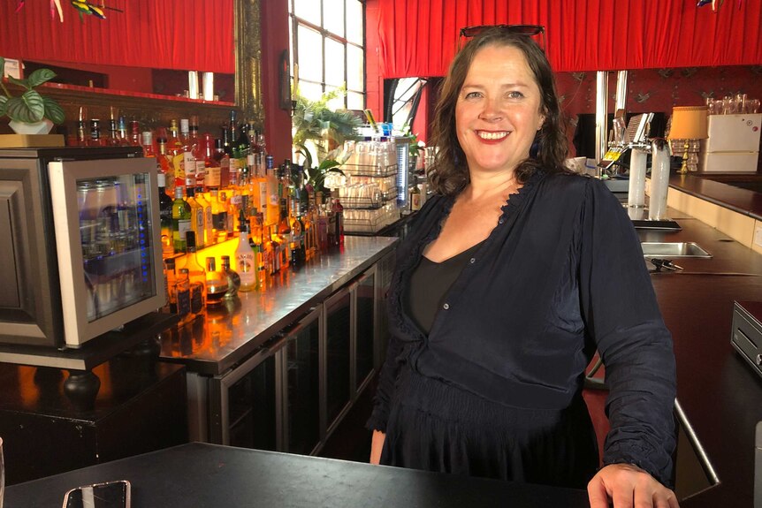 A woman stands behind a bar