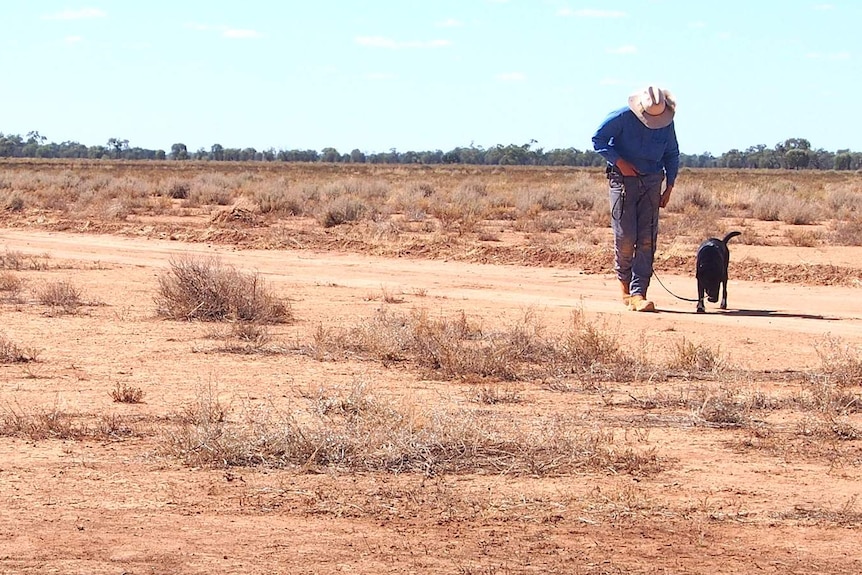 Ethan Reid and his service dog walking through the dry and dusty landscape
