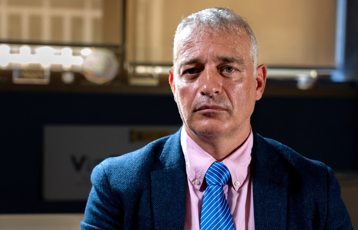 Um homem de terno olhando para a câmera com uma expressão séria.