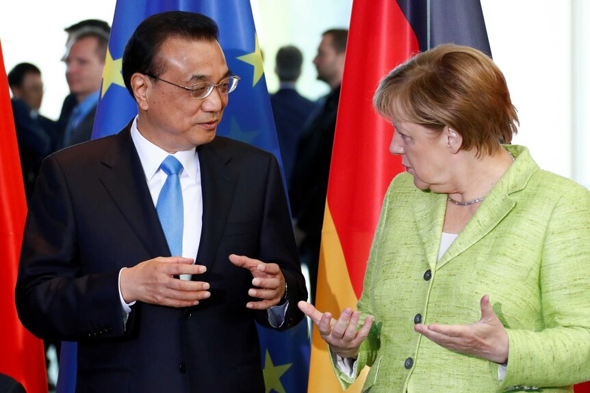 Angela Merkel and Li Keqiang gesture with both hands open in front of a German and EU flag