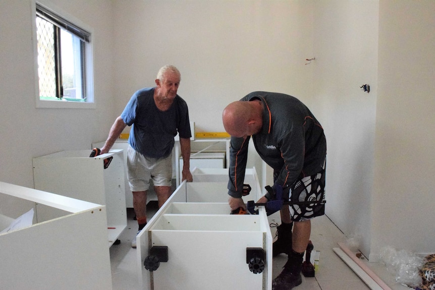 A pair of men making a kitchen in a white house