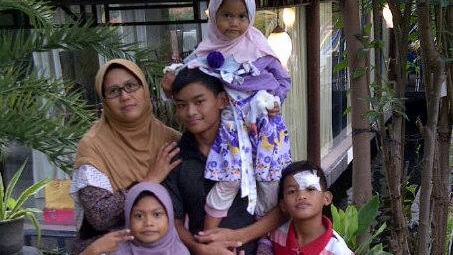 42-year-old Puji Kuswati poses with her four children