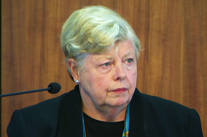 Christine Nixon looks ahead seriously as she sits in front of a microphone in a court building.