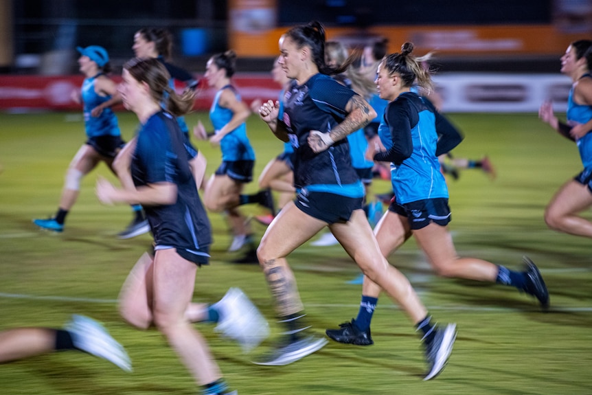 A group of women in blue sportswear running on a field