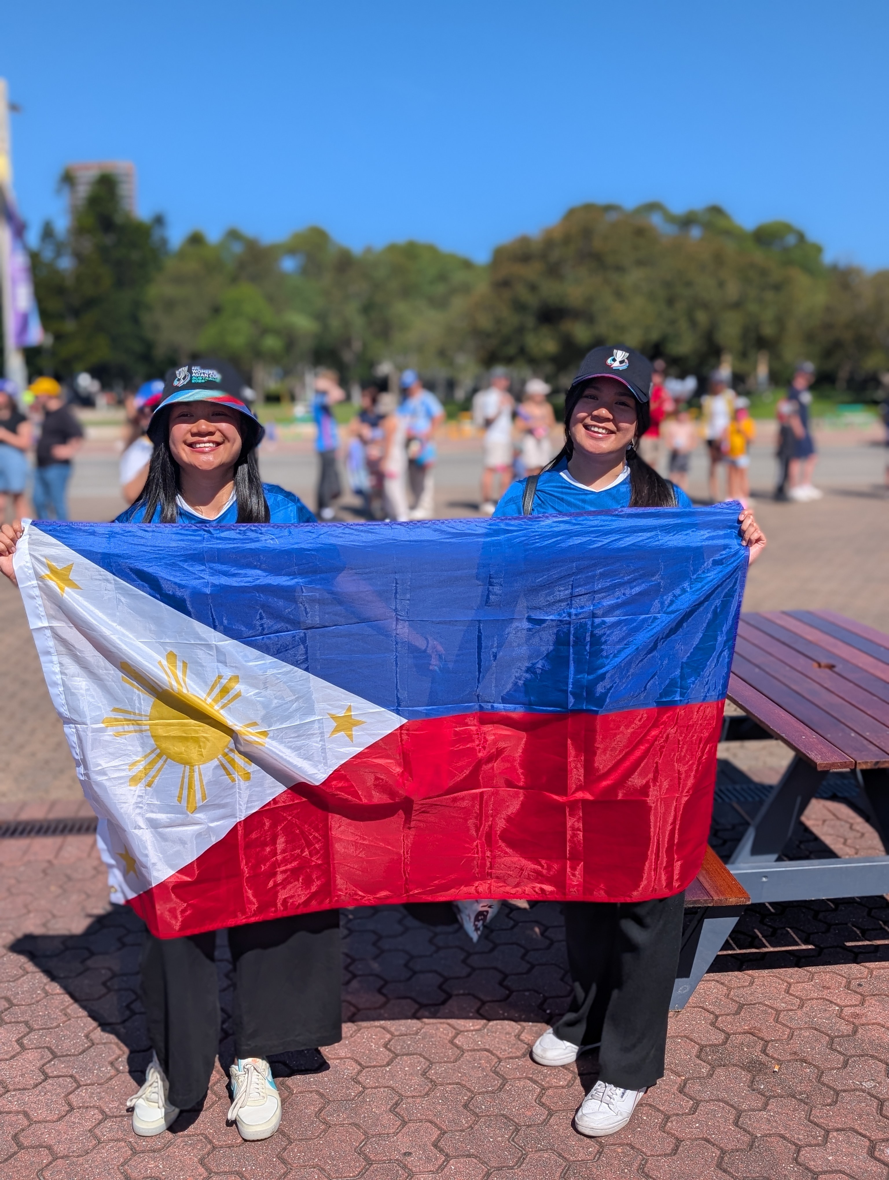 Two women smile and hold a Philippines flag.
