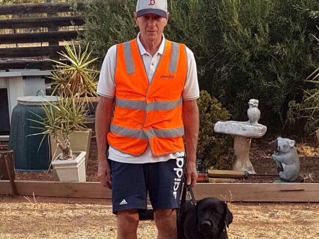 Pensioner Ray Meadows in his trademark hi-vis vest, with his black Labrador guide dog, Gerry.