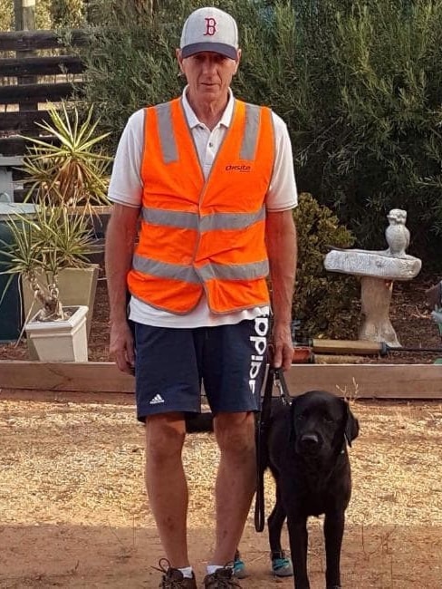 Pensioner Ray Meadows in his trademark hi-vis vest, with his black labrador guide dog, Gerry.