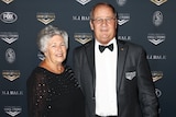 A man wearing a dinner suit poses for a photo alongside his wife at an NRL function in 2018.